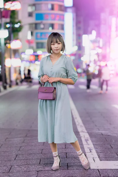 年轻女子夜晚在东京光彩夺目的城市里摆姿势 — 图库照片