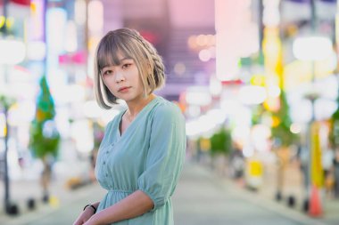 Gece Tokyo 'nun parıldayan şehrinde poz veren genç kadın