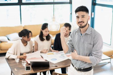 Ofiste poz veren bir iş adamıyla uluslararası iş ekibi.