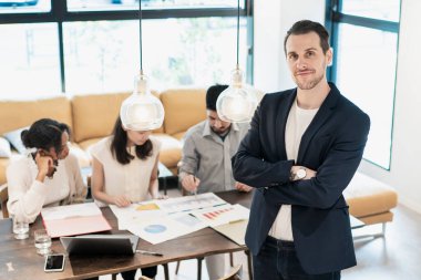 Ofiste poz veren bir iş adamıyla uluslararası iş ekibi.