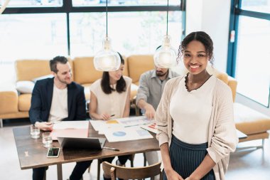 Ofiste poz veren bir iş kadınıyla uluslararası iş ekibi.