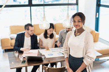 Ofiste poz veren bir iş kadınıyla uluslararası iş ekibi.