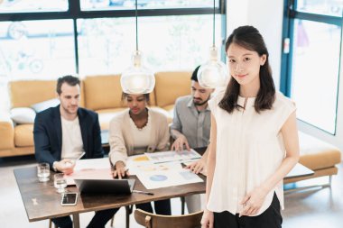 Ofiste poz veren bir iş kadınıyla uluslararası iş ekibi.