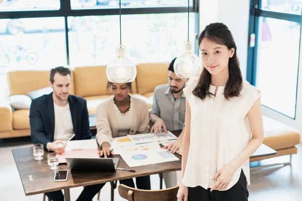 Ofiste poz veren bir iş kadınıyla uluslararası iş ekibi.