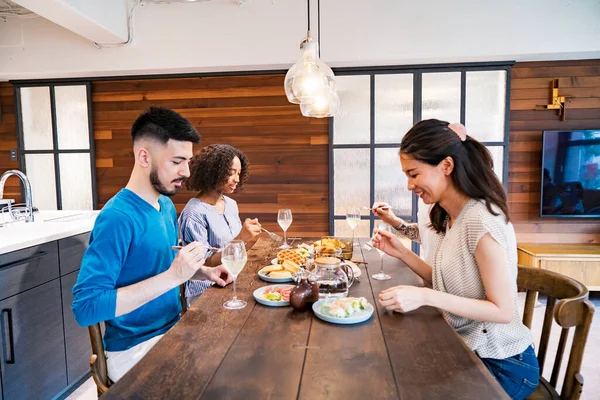 Scene of a home party where men and women surround the dining table