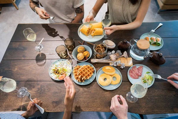 Scene of a home party where men and women surround the dining table