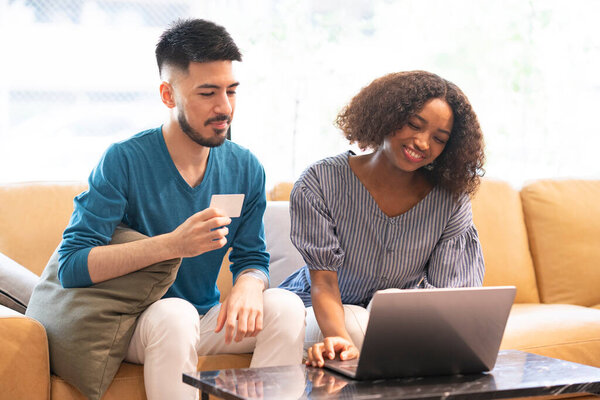 Young man and woman shopping online using laptop and credit card