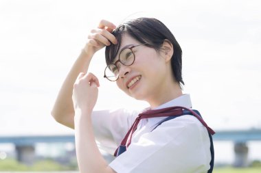 Asyalı liseli kızlar üniforma giyiyor ve okulda gülümsüyor.