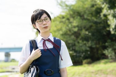 Asyalı liseli kızlar üniforma giyiyor ve okulda gülümsüyor.