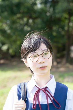 Asyalı liseli kızlar üniforma giyiyor ve okulda gülümsüyor.