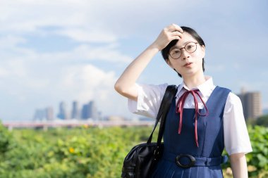 Asyalı liseli kızlar üniforma giyiyor ve okulda gülümsüyor.