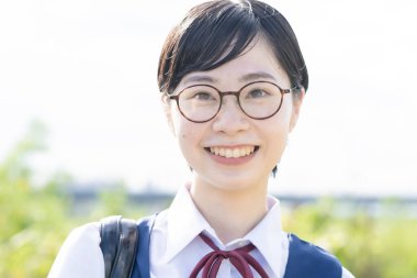 Asyalı liseli kızlar üniforma giyiyor ve okulda gülümsüyor.