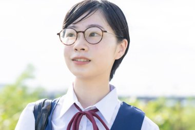 Asyalı liseli kızlar üniforma giyiyor ve okulda gülümsüyor.