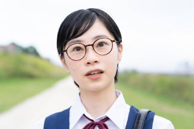 Asyalı liseli kızlar üniforma giyiyor ve okulda gülümsüyor.