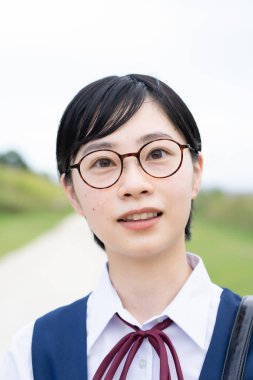 Asyalı liseli kızlar üniforma giyiyor ve okulda gülümsüyor.