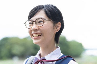 Asyalı liseli kızlar üniforma giyiyor ve okulda gülümsüyor.