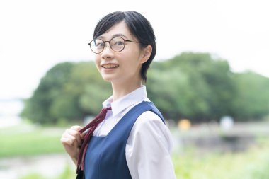 Asyalı liseli kızlar üniforma giyiyor ve okulda gülümsüyor.