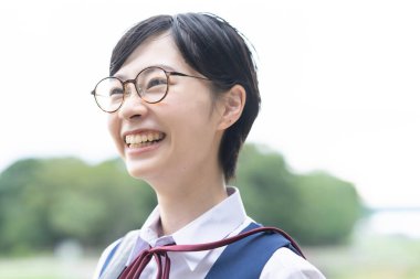 Asyalı liseli kızlar üniforma giyiyor ve okulda gülümsüyor.