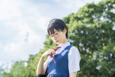 Kısa siyah saçlı, gözlük takan Asyalı liseli kız.