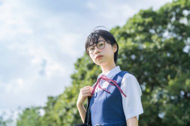 Kısa siyah saçlı, gözlük takan Asyalı liseli kız.