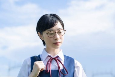 Kısa siyah saçlı, gözlük takan Asyalı liseli kız.