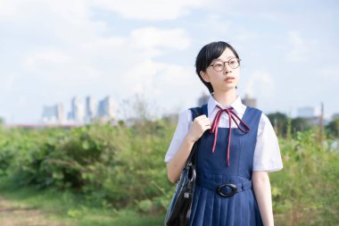 Kısa siyah saçlı, gözlük takan Asyalı liseli kız.