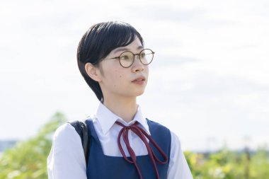 Kısa siyah saçlı, gözlük takan Asyalı liseli kız.