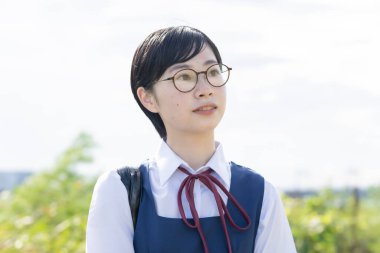 Kısa siyah saçlı, gözlük takan Asyalı liseli kız.