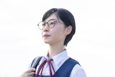 Gözlüklü Asyalı liseli kız gökyüzüne bakıyor.