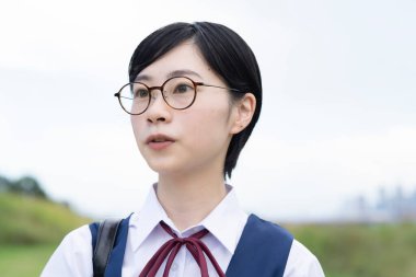 Kısa siyah saçlı, gözlük takan Asyalı liseli kız.