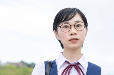 Kısa siyah saçlı, gözlük takan Asyalı liseli kız.