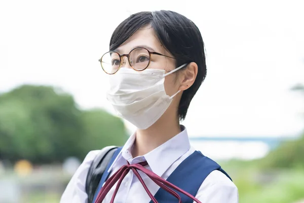 仮面をつけて学校に通うアジア系女子高生 — ストック写真