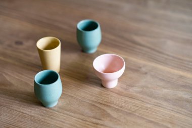 Ahşap yemek masasına dört renkli küçük bardak.