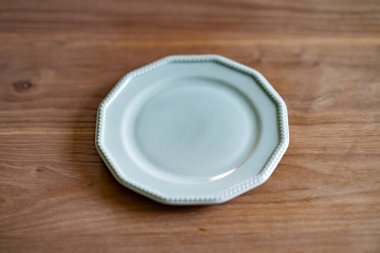 Tahta bir yemek masasına yerleştirilmiş basit bir seramik tabak.