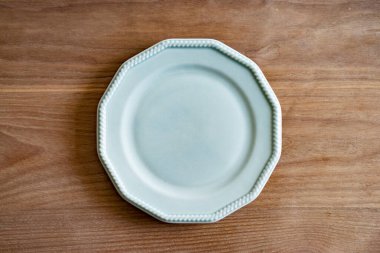 Tahta bir yemek masasına yerleştirilmiş basit bir seramik tabak.