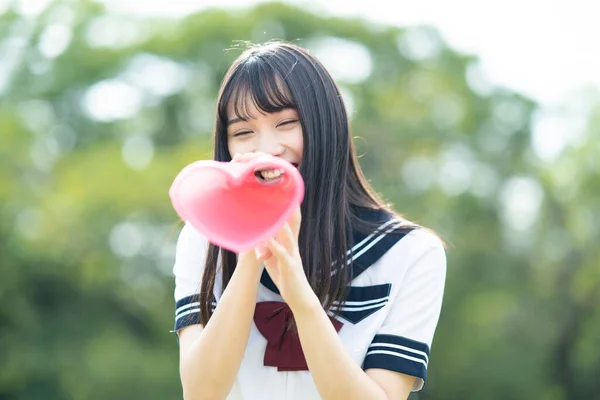 asian high school girl cheering with a heart shaped megaphone