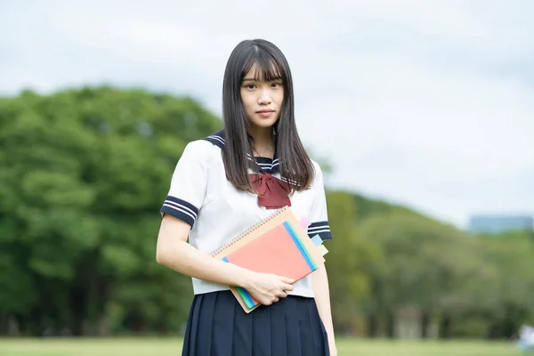 Asian female high school student studying in the park