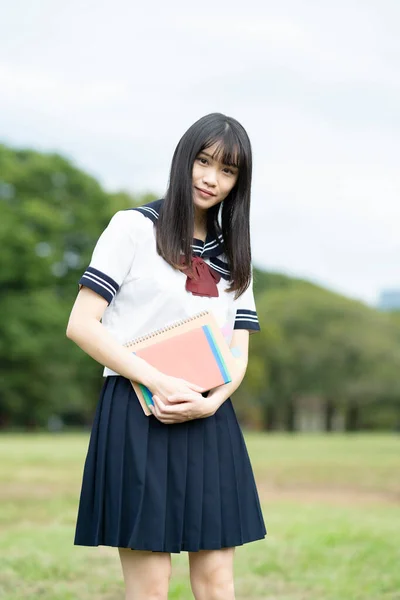 Asian female high school student studying in the park