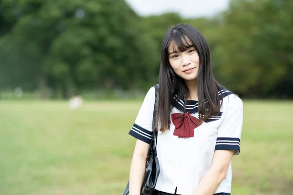 制服を着たアジア系女子高生が笑顔で屋外で — ストック写真