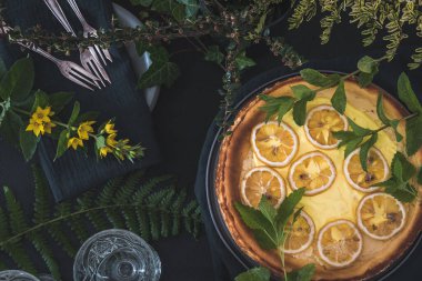 Kurumuş limon dilimli cheesecake ve siyah arka planda süsleme, üst görünüm