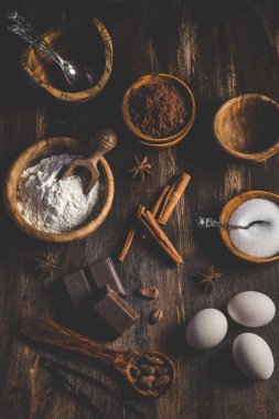 Ahşap bir masa üzerinde, un, yumurta, şeker ve kakao gibi çeşitli hamur işleri.