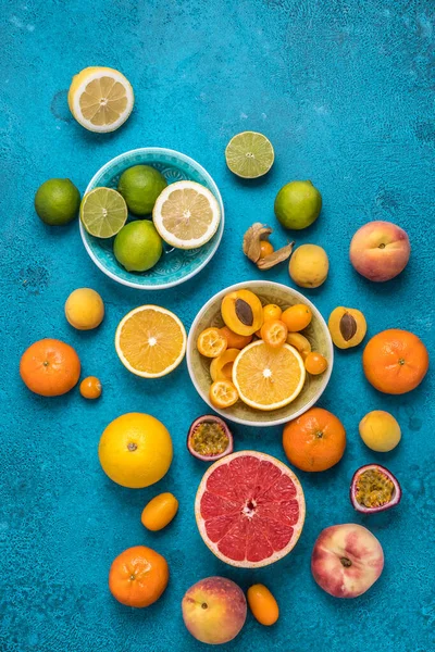 Tropical colorful summer fruits on blue background, vertical top view with copy space