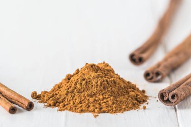 Beyaz tahtaya tarçın tozu ve tarçın çubukları yakın plan. Kopyalama alanı ile.