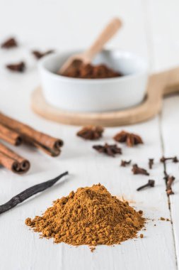 Tarçın, yıldız anason, kakao ve vanilyalı fasulye gibi baharatları beyaz ahşap masada pişirmek. Dikey depo fotoğrafı.