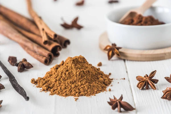 Tarçın gibi baharatlar, beyaz ahşap masa üzerinde yıldız anason ve kakao.