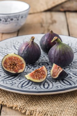 Kırsal ve ahşap üzerinde mavi ve beyaz desenli bir tabakta incir.