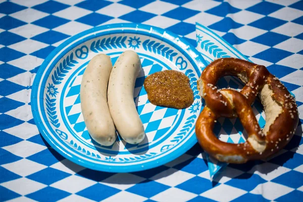 white sausage with sweet mustard and pretzel on blue white plate
