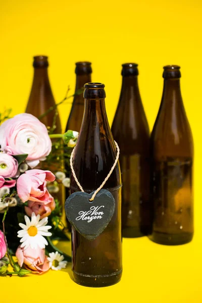 Bierflasche mit Herz und Blumenstrauß im Hintergrund für Vater — Stockfoto