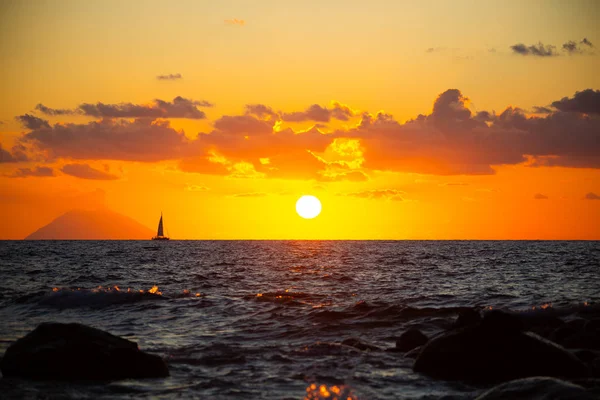 Захід сонця з вітрильним човном перед ним, і стромболі — стокове фото