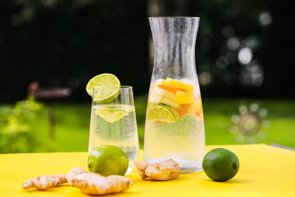 Wasser mit frischen Früchten in Karaffe, grüner Hintergrund, Garten — Stockfoto
